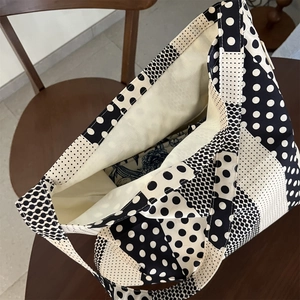 Dettaglio borsa tote in tela a pois bianchi e neri con interno beige e manico robusto