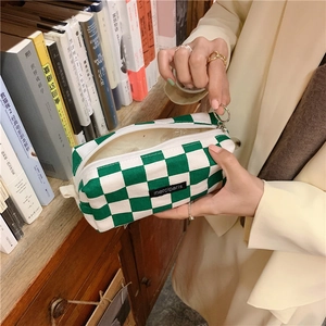Close-up of green checkerboard pencil case with zipper and merciparis logo patch