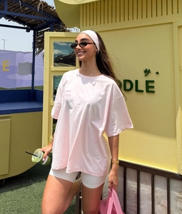 Close-up of pink oversized T-shirt with 'Just Have' print and white cycling shorts