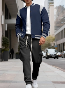 Street style shot of navy blue baseball jacket with black joggers and urban background