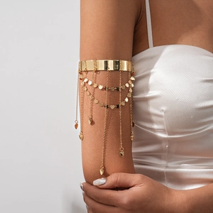 Detail of gold armlet with dangling heart charms and fringe chains on a female arm