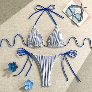 Detail view of white and blue mesh print bikini with gold hardware on sand background