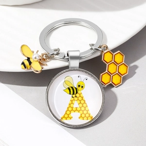 Detail of silver bee keychain with pearl charm, honeycomb and letter A glass pendant