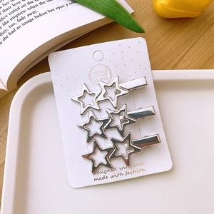 Close-up of three silver hollow star hair clips set on elegant decorative packaging