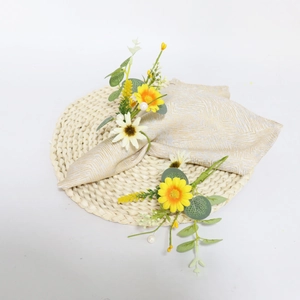 Eucalyptus and daisy napkin rings with pearls on beige fabric napkin over a woven mat