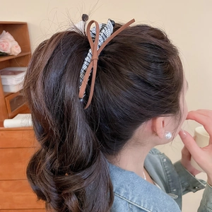 Brown leather bow and checkered dachshund hair clip worn by a model on hair side