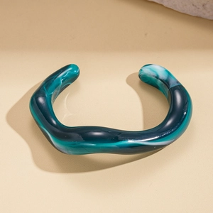 Macro detail of irregular geometric wavy acrylic bangle in green marble resin finish
