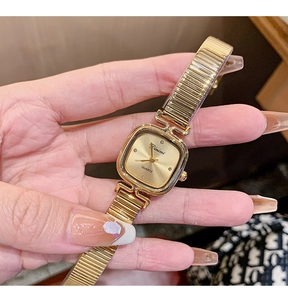 Close-up of a gold square women's watch with crystal markers and elastic metal strap