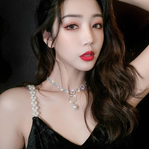 Detail of silver choker with rhinestones and pearl pendant on a velvet dress