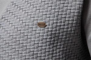 Macro shot of grey knit fabric with premium 3D texture and oval bronze brand emblem