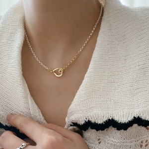Close-up of minimalist gold and silver two-tone pendant necklace on a female model