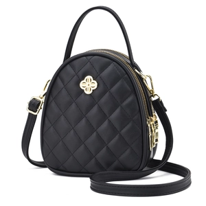 Sac à main matelassé noir chic avec ferrures dorées et poignée sur fond blanc