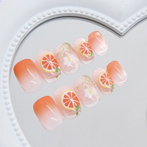 Orangefarbene Farbverlauf-Kunstnägel mit Orangenmotiven und floralen Schleifen