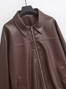 Detail of dark brown faux leather jacket featuring metal zipper and classic collar