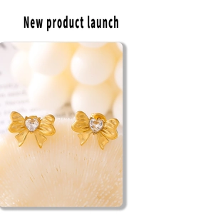 Close-up of golden bow earrings featuring micro-paved heart-shaped cubic zirconia stones