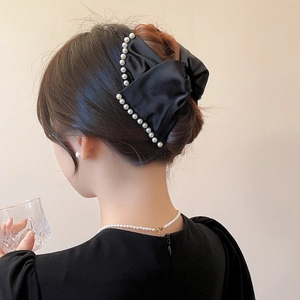 Elegant black satin bow hair claw clip with pearl trim detail shown on a model's hairstyle