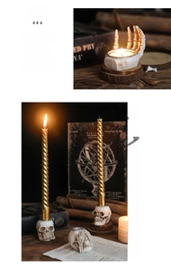 Detail of gothic skull hand candlestick with golden spiral candle on vintage wood background