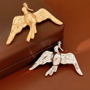 Detailed macro view of gold and silver bird brooches on a premium brown leather jewelry box