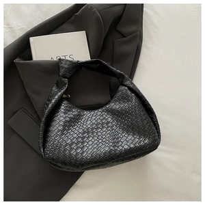 Close-up of black woven hobo bag with unique knot handle detail and textured finish