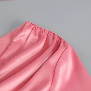 Gros plan détaillé du tissu satin rose avec bords froncés et texture soyeuse du vêtement