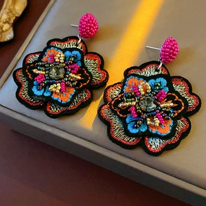 Close-up of colorful embroidered flower earrings with intricate beads and crystals