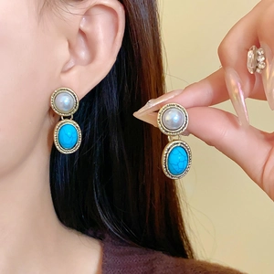 Detail of vintage gold earrings with round white pearls and oval blue turquoise stones