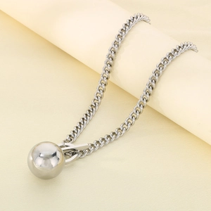 Gros plan du collier gourmette en acier argenté avec pendentif boule et fermoir à bascule