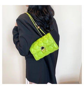 Detail of neon green quilted crossbody bag with metal chain strap and black clasp