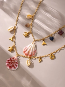 Close-up of shell, sea turtle and fishtail pendants on golden ocean-themed necklace