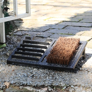 Vintage cast iron boot scraper and brush combo on outdoor stone path for home entrance