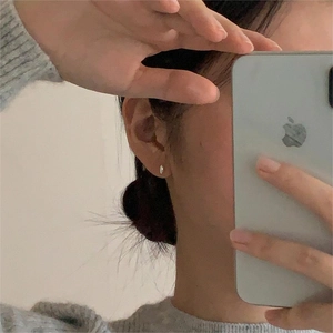 Close-up of minimalist sterling silver oval stud earrings worn on the earlobe