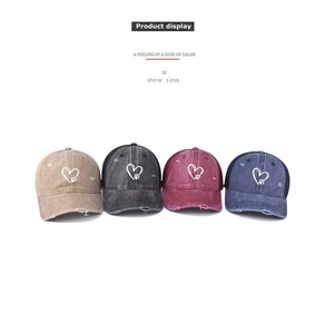 Detail of distressed baseball caps in four colors featuring heart embroidery and mesh back