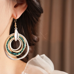 Close-up of bohemian layered hoop earrings with gold, silver and turquoise textured rings