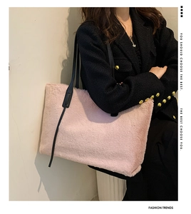 Détail d'un grand sac cabas rose en peluche avec anses noires porté par un mannequin