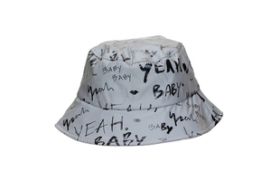 Detailed close-up of grey bucket hat featuring black graffiti print and text patterns