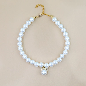 Detailed view of pearl pet collar with rhinestone bow pendant and golden clasp