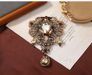 Macro shot of baroque vintage brooch featuring amber crystals and pear-shaped drop pendant