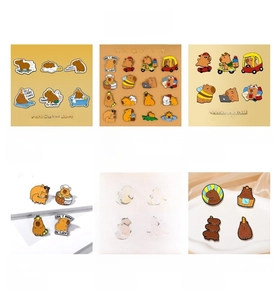 Detail view of colorful enamel pins featuring cute Capybara and lucky cat cartoon characters