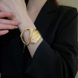 Detail of irregular geometric cutout gold cuff bracelet with textured metallic surface