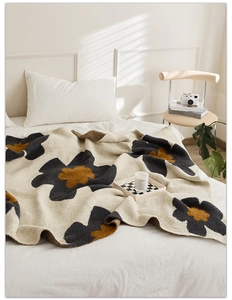 Close-up of beige knit blanket featuring black and yellow sunflower jacquard patterns