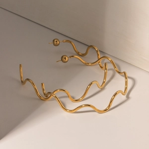 Macro detail of 18k gold plated stainless steel earrings with wavy curve design