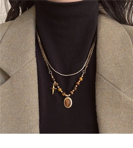 Detail view of double-layered stainless steel necklace with tiger eye stone and cross pendant