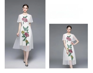 Détail d'une robe en tulle blanc avec broderie florale rose et jaune et bordure ondulée