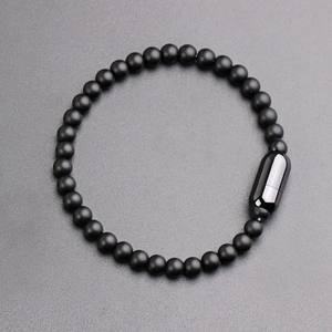 Men's matte black beaded bracelet with sleek stainless steel capsule clasp on grey texture