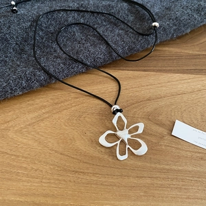 Close-up of S925 silver flower heart pendant on adjustable black cord over a cozy sweater