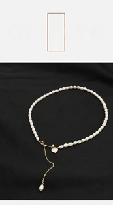 Detail of freshwater pearl necklace with gold clasp and heart pendant on black fabric
