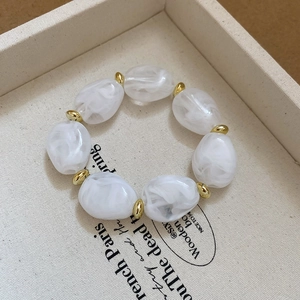 Detail of irregular white marble beads bracelet with golden spherical spacers