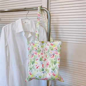 Floral cotton tote bag with colorful watercolor prints hanging beside a white shirt