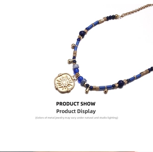 Detailed view of beaded necklace with gold sun relief pendant and blue beads