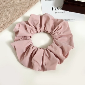 Macro view showing the smooth texture and layered folds of the large pink satin scrunchie